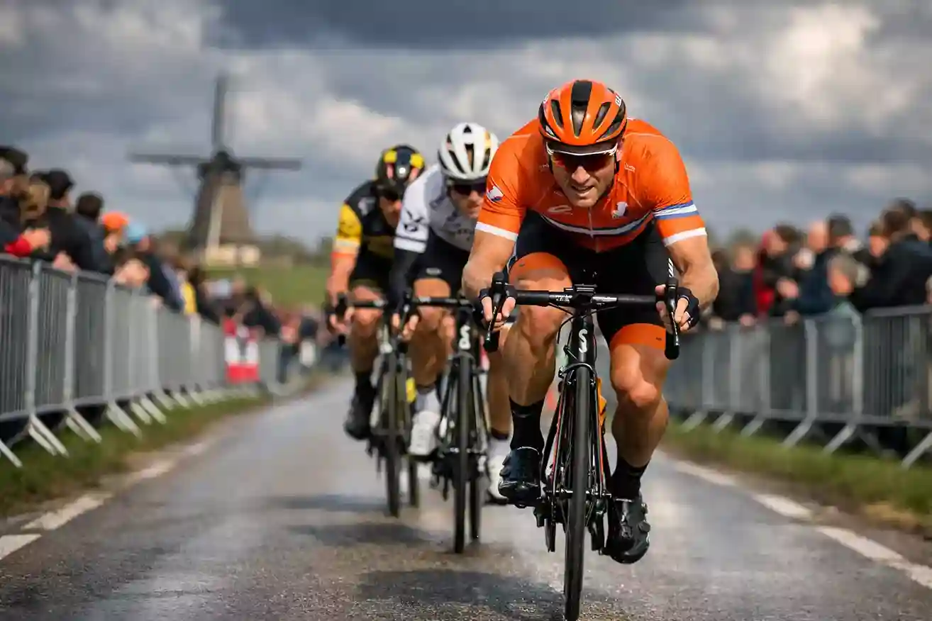 Nederlandse wielrenner in oranje tenue rijdt aan kop van een groep tijdens voorjaarsklassieker